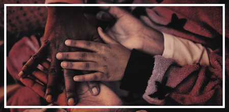 Family forming hand stack while playing on bed in bedroomの写真素材