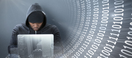 Focused male hacker using laptop  against panoramic shot binary codes on blue screen