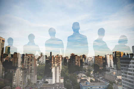 Business people standing against white background against city against blue skyの写真素材