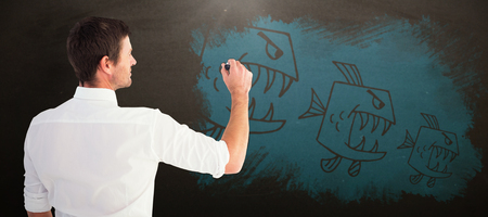 Business man writing with chalk against blackboardの写真素材