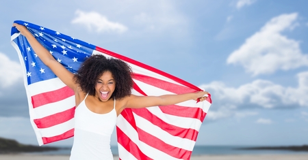 Digital composite of Happy woman holding a USA flag in the beachの写真素材