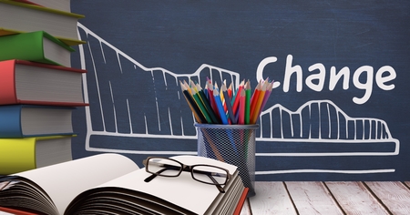 Digital composite of Books on the table against blue blackboard with education and school graphicsの写真素材