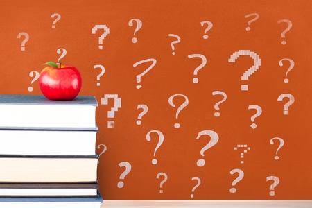 Digital composite of Books on the table against orange blackboard with question marksの写真素材