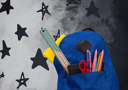 Digital composite of Schoolbag on Desk foreground with blackboard graphics of stars