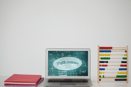 Digital composite of Computer on a school table with school icons on screen