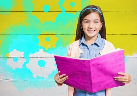 Digital composite of Girl holding book in front of yellow painted wall with cog gear settingsの写真素材