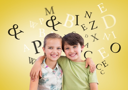 Digital composite of Many letters around Boy and girl hugging in front of yellow backgroundの写真素材