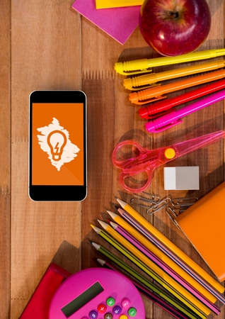 Digital composite of Phone on a school table with bulb icon on screenの写真素材