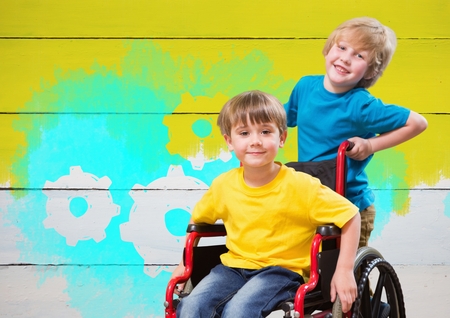 Digital composite of Disabled boy in wheelchair with painted yellow background and settings cogs gearsの写真素材
