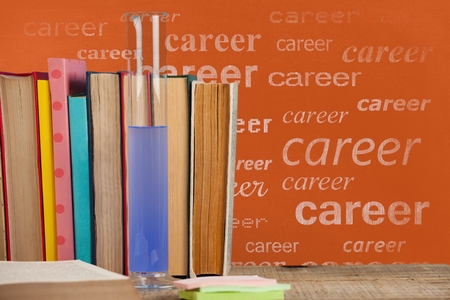 Digital composite of Books on the table against orange blackboard with career textの写真素材