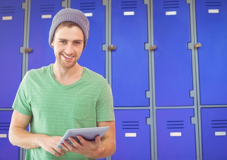 Digital composite of male student holding tablet in front of lockersの写真素材