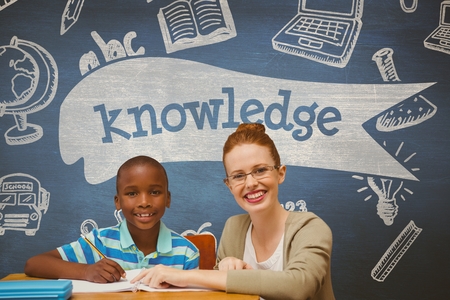 Digital composite of Happy student boy and teacher at table against blue blackboard with knowledge text and education andの写真素材