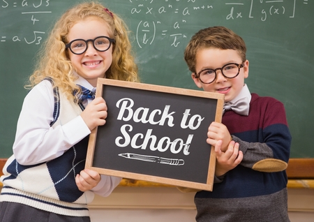 Digital composite of back to school text on blackboard with two school kidsの写真素材
