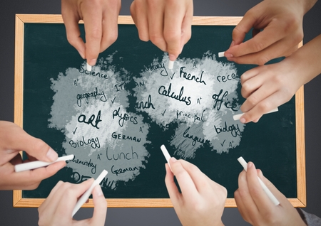 Digital composite of Many Hands writing school subjects on blackboardの写真素材