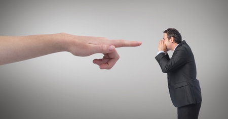 Digital composite of Hand pointing at angry business man against grey backgroundの写真素材