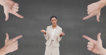 Digital composite of Hands pointing at confused business woman against grey backgroundの写真素材