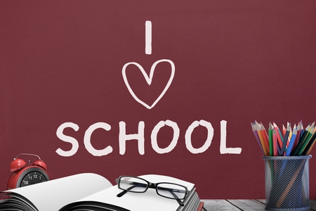 Digital composite of Books on the table against red blackboard with I love school textの写真素材