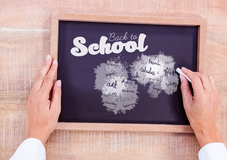 Digital composite of Hand writing school subjects and back to school text on blackboardの写真素材
