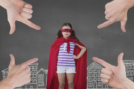 Digital composite of Hands pointing at girl in a super heroine custom against grey background with city illustrationの写真素材