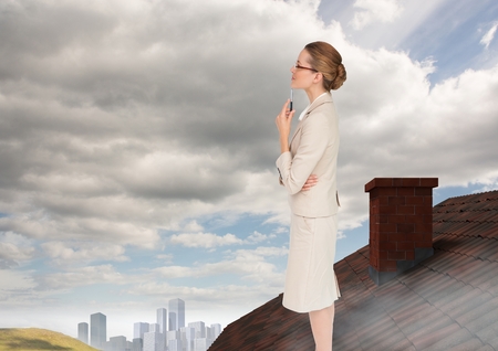 Digital composite of Businesswoman standing on Roof with chimney and city in distanceの写真素材