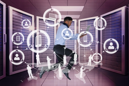 Digital composite of Business man holding a computer and graphics in server room