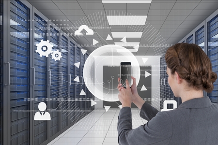 Digital composite of Business woman holding a phone and graphics in server room