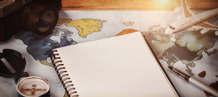 High angle viewof Diary by camera and toy airplane on map at table