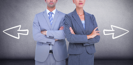 Business people with arms crossed looking at camera against grey roomの写真素材