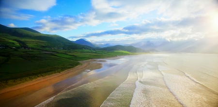 Idyllic view of mountain by sea against cloudy sky