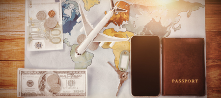 Directly above shot of toy airplane with currency and passport by smartphone on map at table