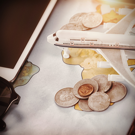 Close up of toy airplane with coins and tablet computer on mapの写真素材