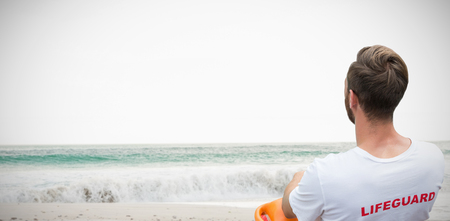 Rear view of male lifeguard sitting on chair against scenic view of waves on seashore