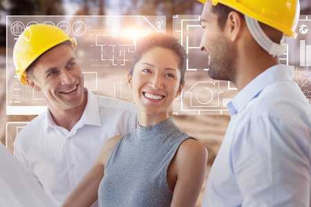 Happy architect discussing over blueprint against high angle view of muddy construction siteの写真素材