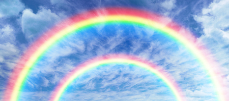 Digitally generated image of rainbow against view of overcast against blue skyの写真素材