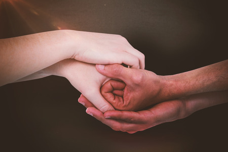 Cropped hands holding together against blackboard