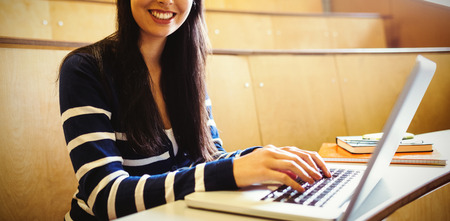 Smiling student using laptop at desk in university