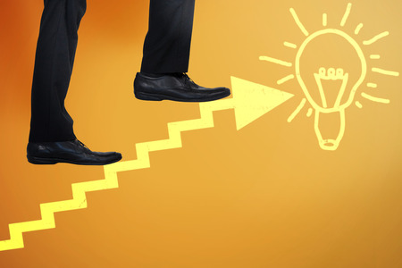 Low section of businessman climbing steps against yellowの写真素材