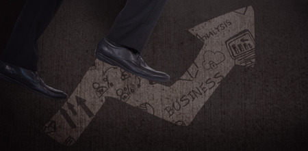 Low section of businessman climbing steps against graphic image of business graphの写真素材
