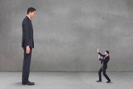 Digital composite of Scared small business man looking at a big business manの写真素材