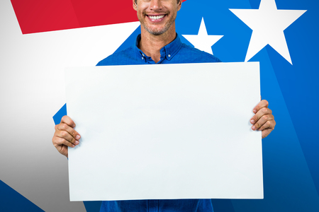 Portrait of happy man holding placard against digital composite of american flagの写真素材