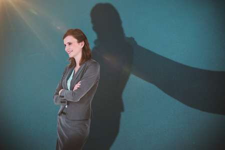 Smiling businesswoman with arms crossed against blueの写真素材