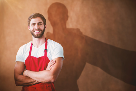 Portrait of smiling confident male owner with arms crossed against brown grocery bag textureの写真素材