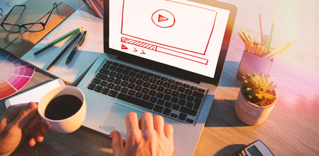 Video interface against cropped hands of male executive working over laptop at deskの写真素材