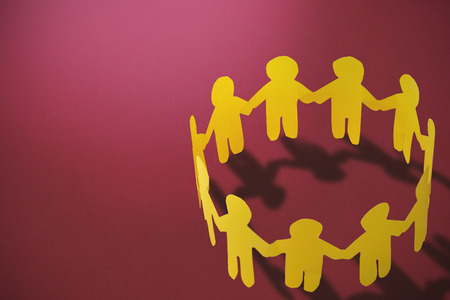 group of yellow little person holding hands against red backgroundの写真素材