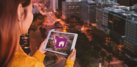 Smiling asian woman using tablet against glowing roads by building in cityの写真素材