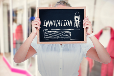 Woman with face covered by chalkboard against blurry front shopの写真素材