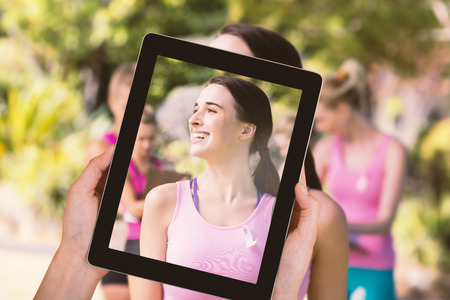 Close-up of hands holding digital tablet against female volunteer smiling while looking awayの写真素材