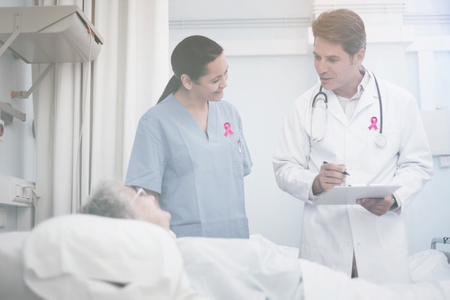 Breast cancer awareness ribbon against doctor and nurse talking to patientの写真素材