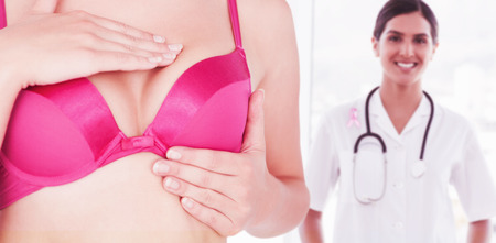 Mid section of woman in pink bra checking breast for cancer awareness against close-up of prostate cancer awareness ribbonの写真素材