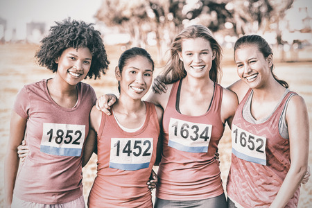 Portrait of four smiling runners supporting breast cancer marathon in parklandの写真素材
